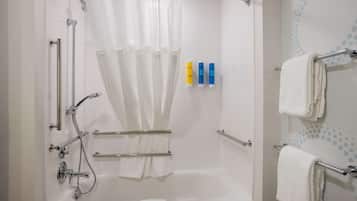 Un baño moderno con bañera, ducha y barras de apoyo.