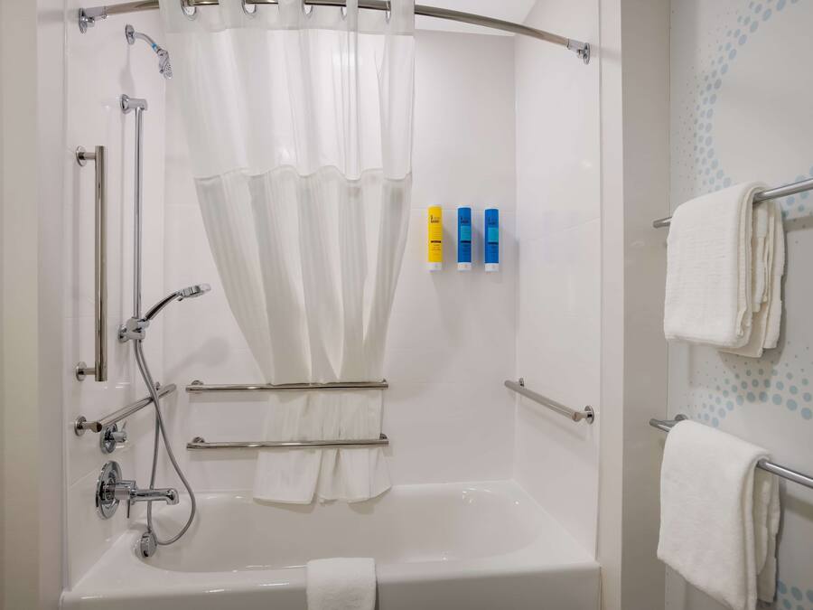Un baño moderno con bañera, ducha y barras de apoyo.