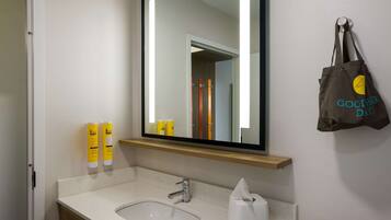 A bathroom with a sink, mirror, and toiletries.