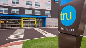 L'ingresso di un hotel con un attraversamento pedonale ben visibile, un tendone blu e giallo e una segnaletica che indica la proprietà Hilton.