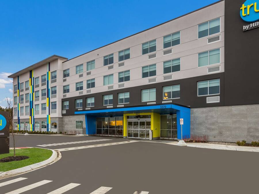 A modern hotel with a blue and grey facade, a prominent entrance, and a clear sky.