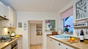 A kitchen with wooden countertops, white cabinets, a built-in microwave, and a window with a view of the sea. - A bright and spacious three bedroom house with panoramic views over Looe. (Looe)