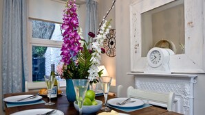 A dining table set with plates, cutlery, a bowl of apples, and a vase of flowers. - A bright and spacious three bedroom house with panoramic views over Looe. (Looe)