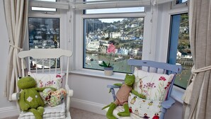 A room with two rocking chairs, one white and one blue, each with a plush frog toy. - A bright and spacious three bedroom house with panoramic views over Looe. (Looe)