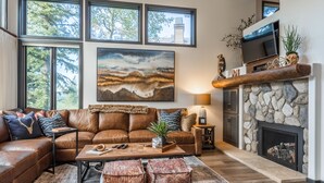 A cozy living room with a brown leather sofa, a coffee table, and a fireplace with a stone surround. - On Golf Course Fully Renovated Luxury 4 Bedrm 3 Full Bathrms and Half Bath Snowcreek 732 Phase V (Mammoth Lakes)