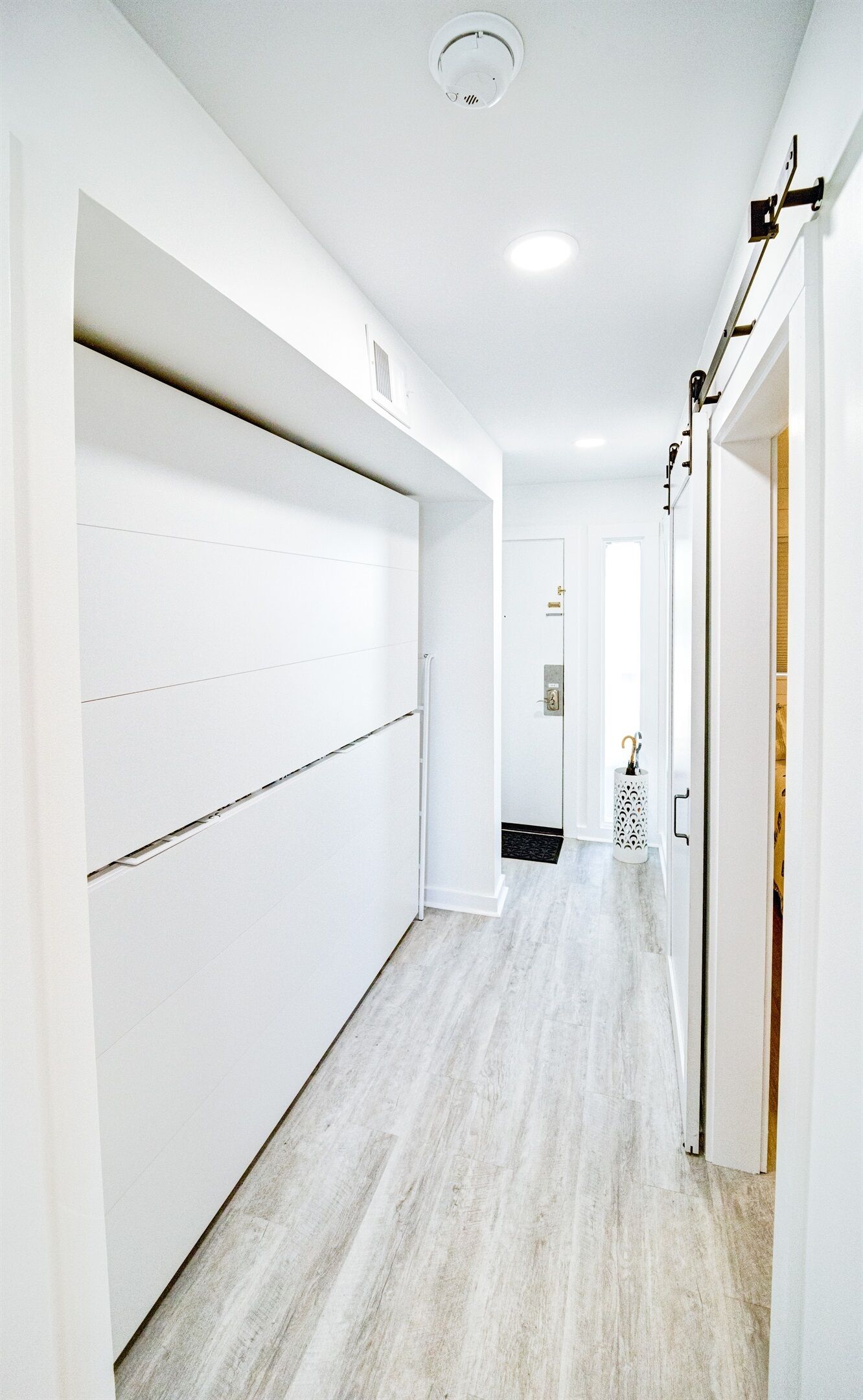 En stilren, modern hall med en garageport, en dörr med en dekorativ detalj och en lampa i taket.