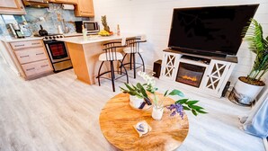 Et moderne køkken med en central ø, barstole, et fladskærms-tv og en pejs.