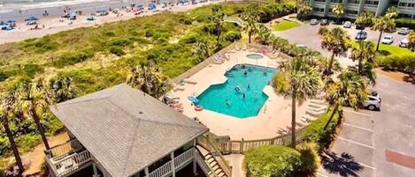 A resort with a swimming pool, beach, and parking area.