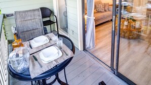 En overdækket terrasse med et bord dækket til to, en stol og en dekorativt placeret skibsrod på væggen.