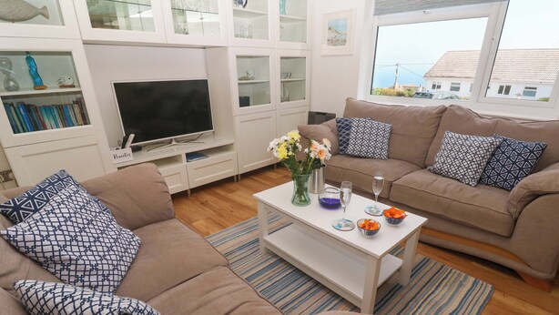Una sala de estar con sofá, mesa de centro, televisor y ventana con vistas.