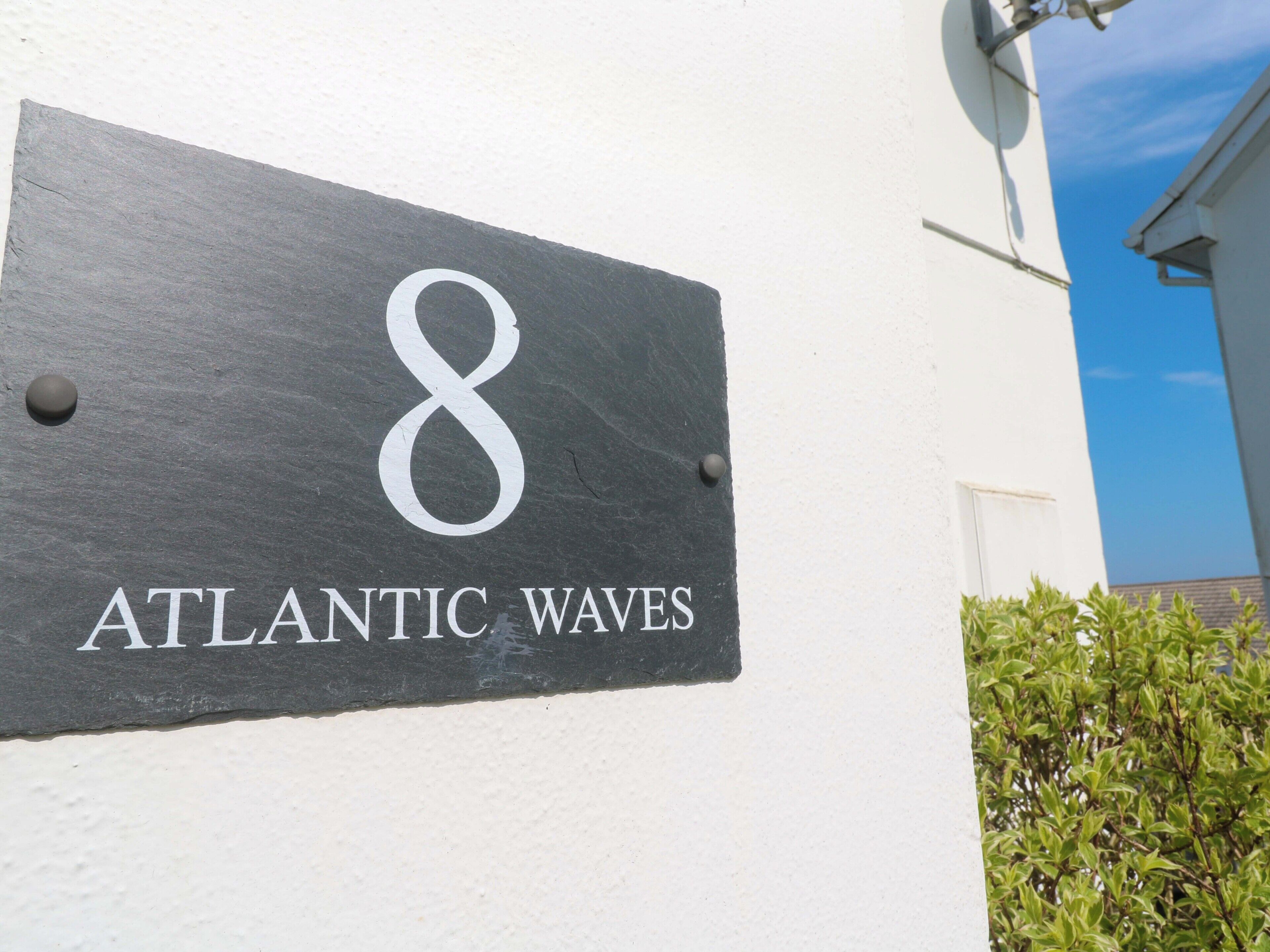 Segnaletica in ardesia con il numero 8 e la scritta 'ATLANTIC WAVES' su una parete bianca.