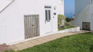 Un edificio blanco con puerta de madera, una ventana pequeña y una antena parabólica.