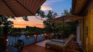 Una terraza con mobiliario exterior, vistas a un lago y un atardecer.