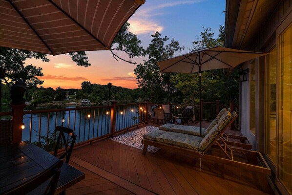 Una terraza con mobiliario exterior, vistas a un lago y un atardecer.