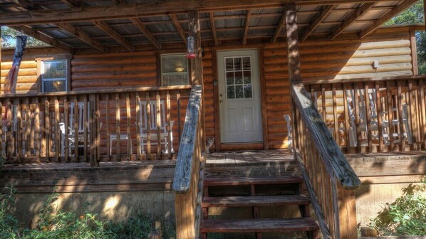 Une cabane en bois avec une véranda, une porte et une fenêtre.