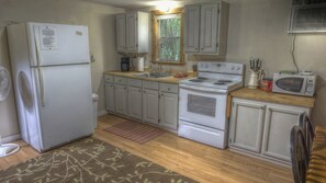 Une cuisine compacte équipée d’un réfrigérateur, d’une cuisinière, d’un four à micro-ondes et d’une fenêtre située au-dessus de l’évier.