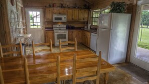 Cocina de cabaña de madera con una mesa de comedor, sillas, un refrigerador, un microondas, un horno y un lavavajillas.