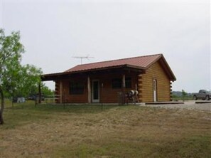 A wooden cabin with a red roof, a front door, and a small porch. - Old Glory River Cabin (Utopia)