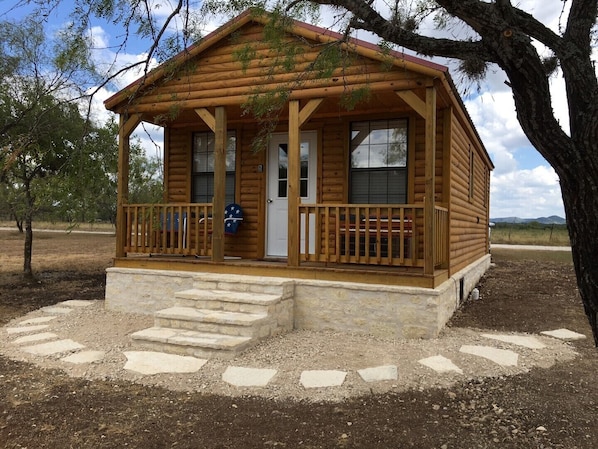 A wooden cabin with a porch, stone steps, and a mailbox.