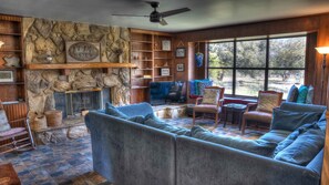 A cozy living room with a stone fireplace, a large sofa, and a television.