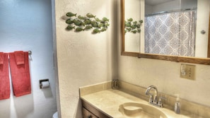 A bathroom with a beige sink, a mirror, and a red towel.