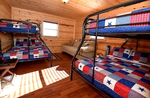 A cabin with three bunk beds, a sofa, and a window.