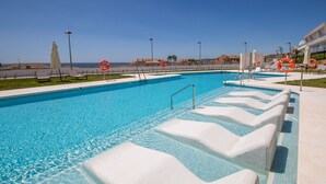 A clear blue swimming pool with steps leading into the water, surrounded by a fence and beach chairs. - Celere Dona Julia 2.3.0b (Casares)