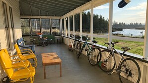 Une véranda abritée avec des sièges, des vélos et une vue sur un lac.