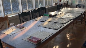 Une table de salle à manger en bois, avec des tapis de jeu en forme de puzzle, un verre à vin et une serviette.