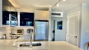 A modern kitchen with a large island, stainless steel appliances, and a view of the living area.
