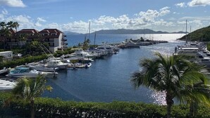 A marina with boats docked, surrounded by buildings and palm trees.