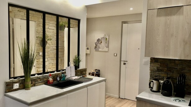 Een moderne keuken met witte kasten, een backsplash van natuursteen en een houten aanrecht.