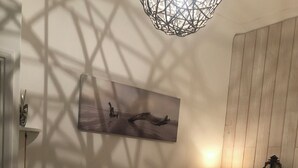 Een slaapkamer met twee bedden, een houten wand, een schilderij, een hanglamp en een wandlamp.