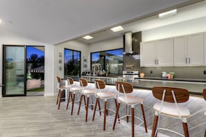 A modern kitchen with a dining area, featuring a large island, stainless steel appliances, and a view of the outdoors. - Pool, Sauna, Hot tub. Location! military discount (Scottsdale)