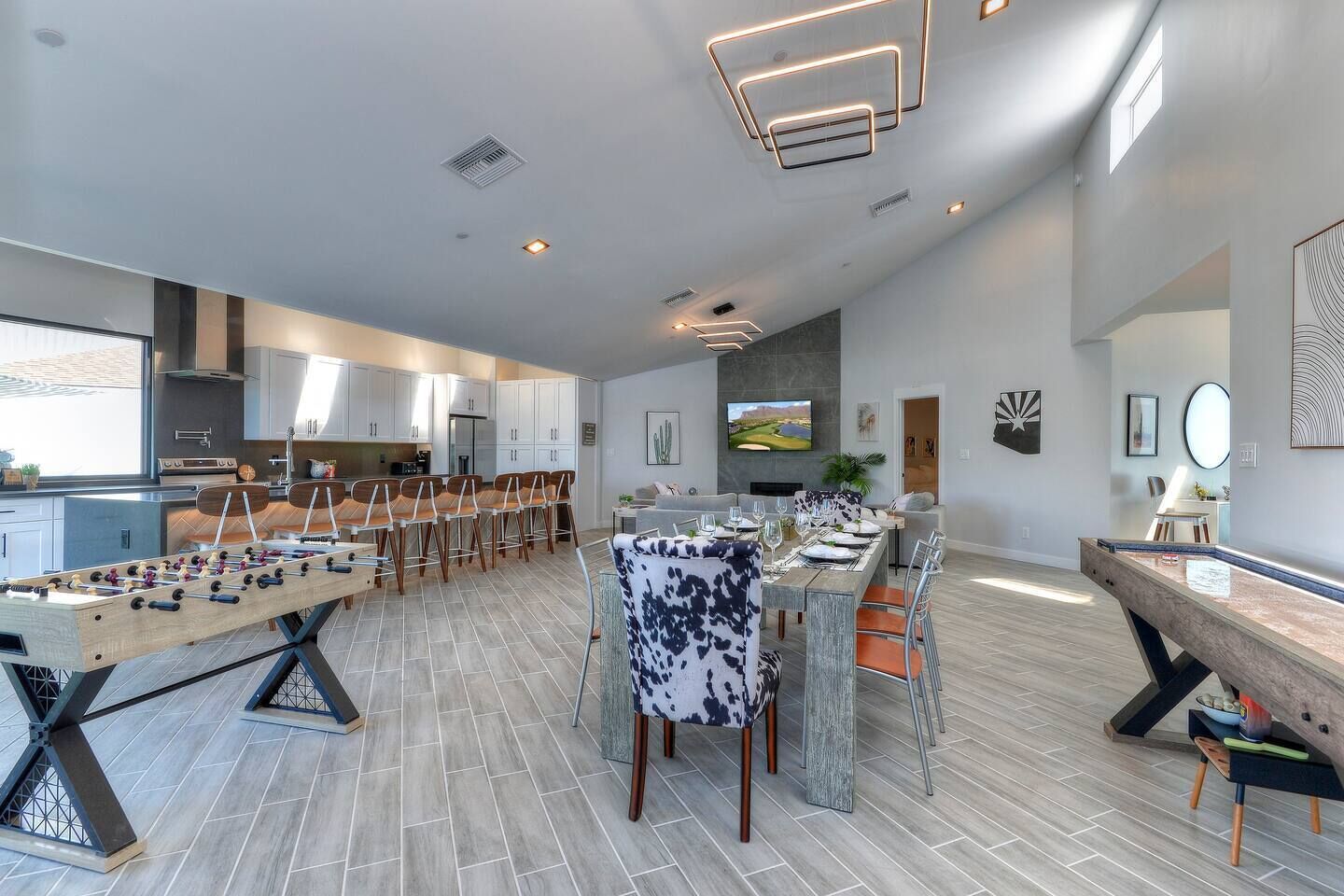 Une cuisine spacieuse équipée d’appareils modernes, un coin repas avec un baby-foot et un salon doté d’un téléviseur et d’œuvres d’art.
