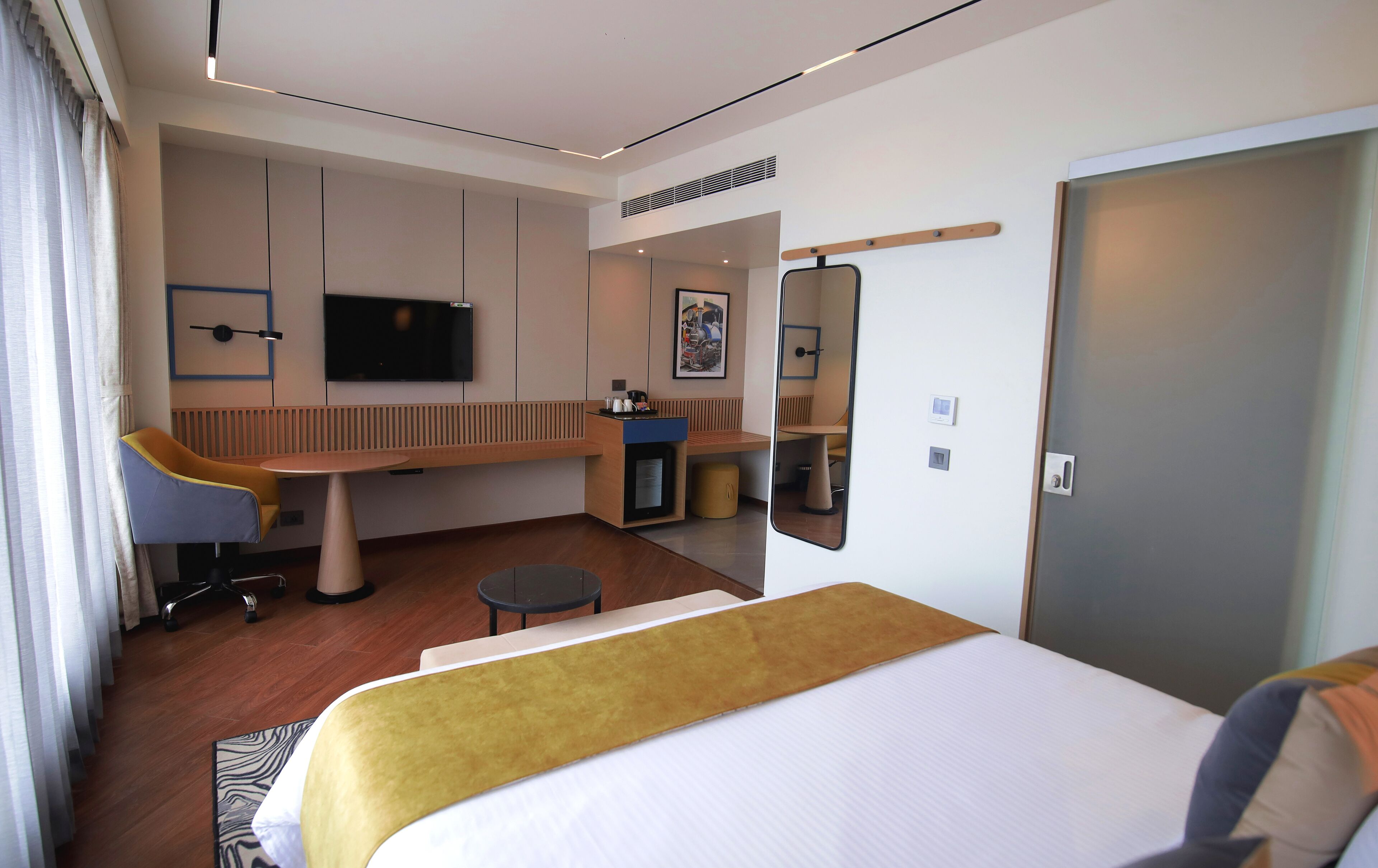 Una habitación de hotel con cama, escritorio, silla, televisión y baño.
