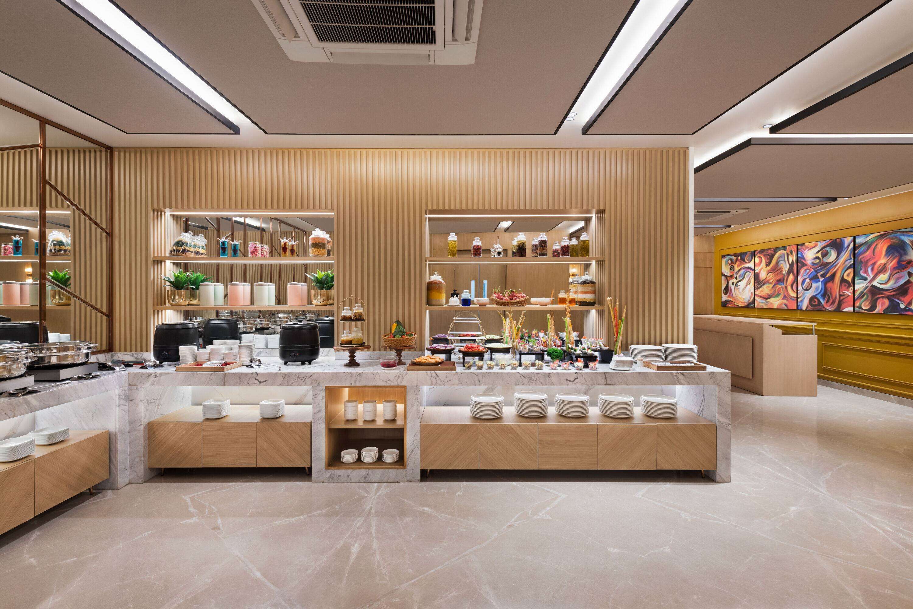 A modern hotel lobby with a marble reception desk, wooden paneling, and a colorful abstract painting on the wall.