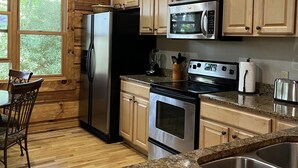 A modern kitchen with wooden cabinets, stainless steel appliances, granite countertops, and a dining area with a wooden table and chairs. - "Deacon Escape", incredible and quiet getaway. (Newland)