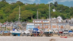 A harbor with boats, a gravel beach, and residential buildings in the background. - Coast View Apartment (Lyme Regis)