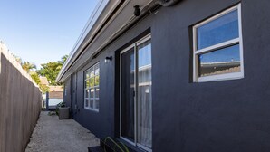 Una casa moderna con fachada oscura, grandes puertas correderas de vidrio y un pequeño porche.