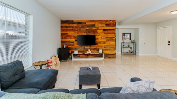 Una sala de estar moderna con una pared decorada con madera, un televisor de pantalla plana, un sofá, una mesa de centro y una mesita auxiliar.