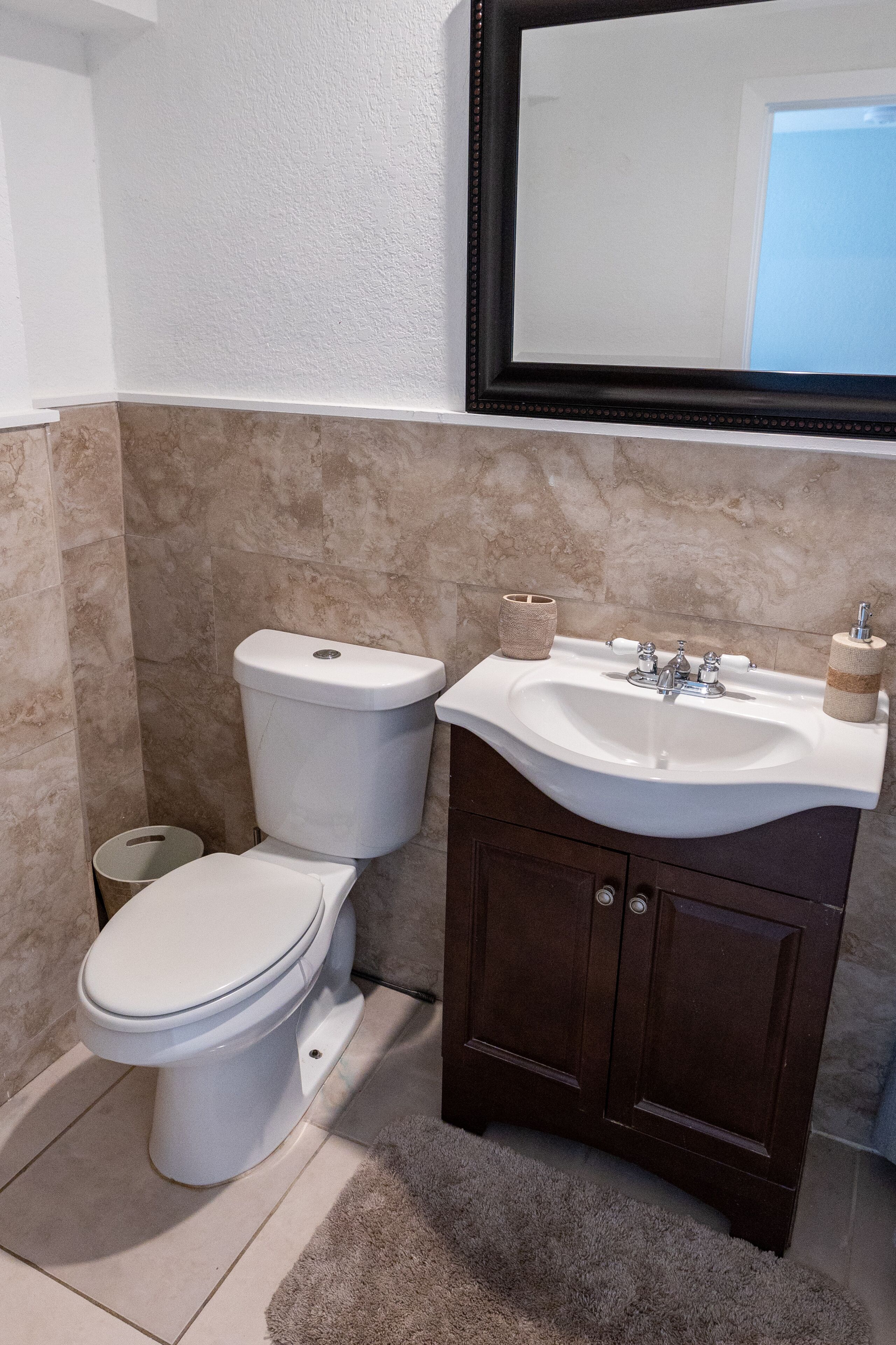 Un baño con inodoro, lavabo y espejo.