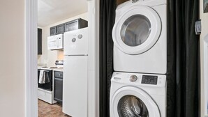 A laundry room with stacked washers and dryers, a microwave, and a stove.