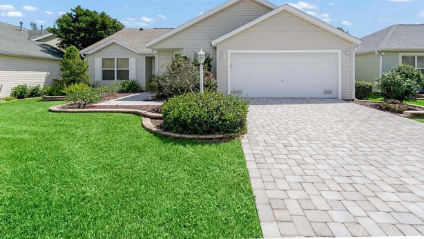 A residential house with a garage, well-maintained lawn, and a paved driveway. - Close to Pelican Heron Golf Course and only  7 minutes to Lake Sumter Landing (The Villages)