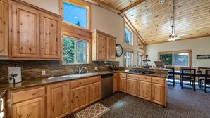 A spacious kitchen with wooden cabinets, granite countertops, and a large island. - The Restful Rose ~ Fireside Vibes + AC Comfort (Shaver Lake)