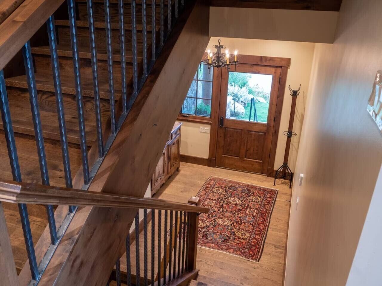 A wooden staircase leading to a room with a door, a chandelier, and a rug.