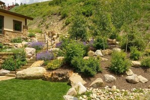A hillside with a stone staircase leading up to a building, surrounded by various plants and rocks. - INCREDIBLE views 1 block to ski area, free bus to town, hot tub, (Crested Butte)