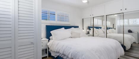 Un dormitorio con una cama grande, una mesita de noche, un aparador y un espejo.
