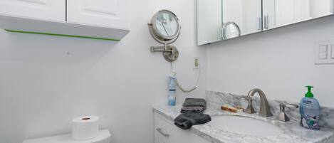 A bathroom with a toilet, sink, and mirror.