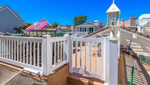 A residential area with a white fence, a small tower-like structure, and a large American flag. - 3 Properties From the Beach (Newport Beach)